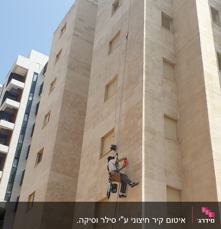 אדם על חבל מבצע איטום קיר חיצוני